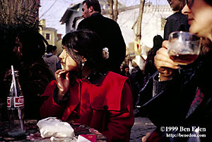 A girl in a red coat scratches her chin after she had finished her Coca-Cola bottle, waiting for her mother to finish her cup of tea on a winter afternoon at an Ortakoy cafe in Istanbul, Turkey.