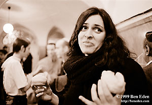 A beautiful young Czech Jewish woman with long black hair looks astray while holding two sufganias (donuts) at a Prague Jewish Community Chanukah (Hanukah) celebration.