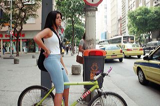 A carioca girl waits on her mountain bike to cross a busy street in Rio de Janeiro, Brazil
