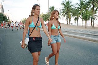 Two young blonde women in turqoise bikini tops walk next to each other along the Ipanema beach in Rio de Janeiro, Brazil