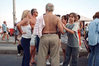 A brazilian family on a Sunday outing by Ipanema beach in Rio de Janeiro. A middle-aged, balding man with a hairy back is being alerted by his son