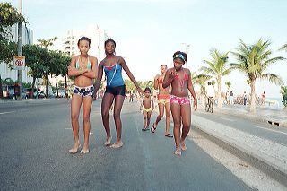 Brazilian children, probably from one of Rio's favelas, dressed-up in bikini tops walk by Ipanema Beach in Rio de Janeiro, Brazil